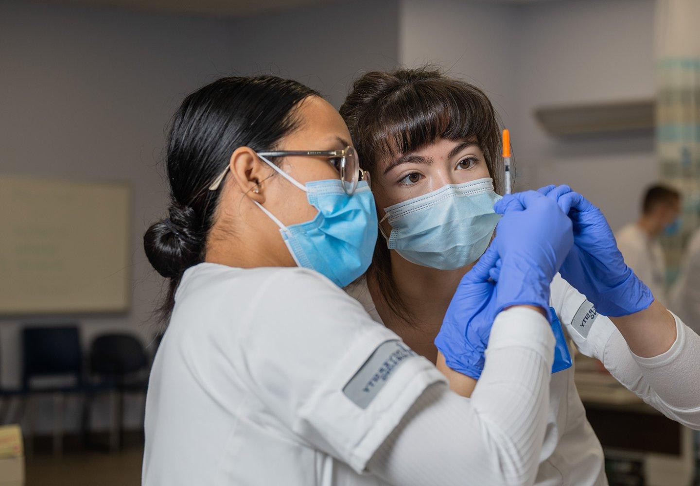 Two nurses look at a vial